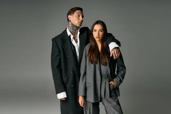 A fashionable young couple displays confidence in elegant gray attire, showcasing modern style. — Stock Photo