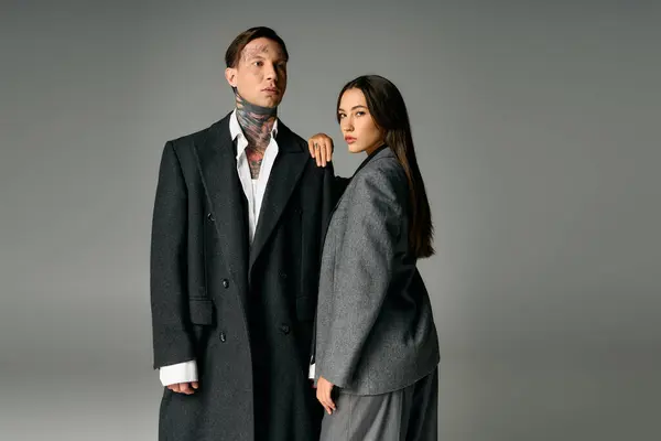 Attractive young couple stands confidently, showcasing modern fashion in a sleek studio. — Stock Photo