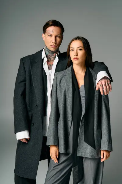A trendy pair stands elegantly together, showcasing unique attire and strong expressions. — Stock Photo
