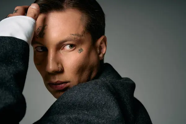 A young man showcases unique tattoos while staring with an enigmatic expression. — Stock Photo