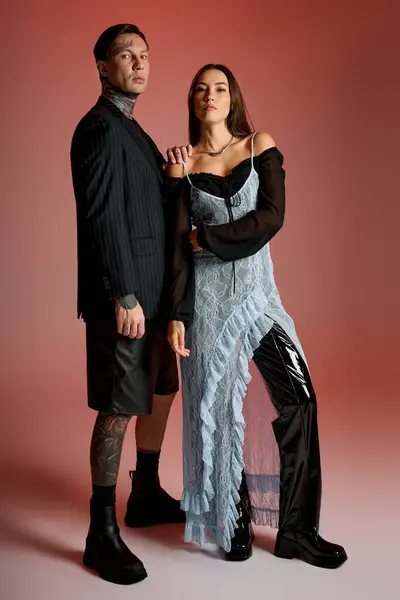 A fashionable pair stands confidently, showcasing modern outfits in a vibrant setting. — Stock Photo