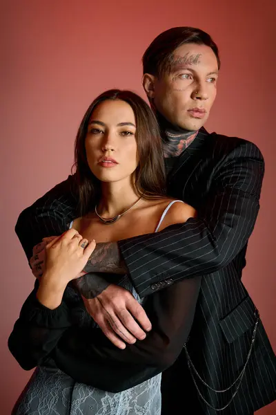 Attractive couple embraces closely, highlighting their fashion choices and striking features. — Stock Photo