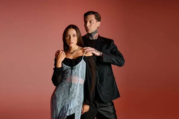 A young couple showcases unique fashion while standing against a vivid background. — Stock Photo