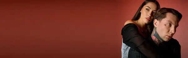 The couple stands intimately, expressing connection and style amid a rich red background. — Stock Photo