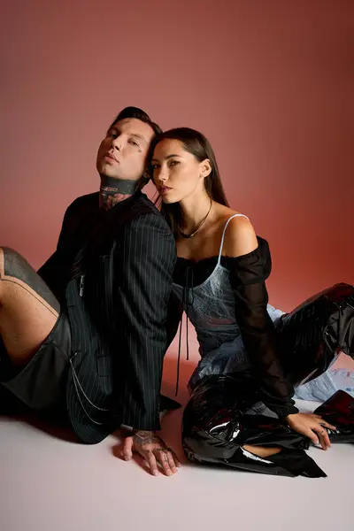 A young couple showcases their fashionable outfits while sitting side by side in a creative studio. — Stock Photo