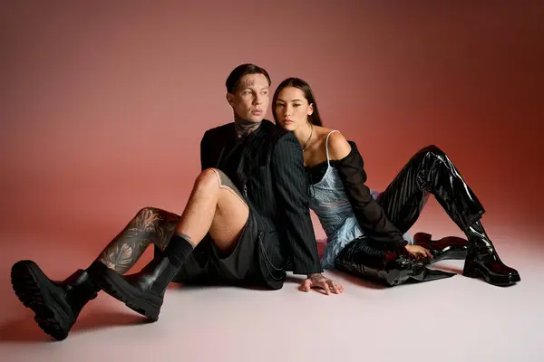 A stylish pair poses back to back, displaying unique styles in a studio setting. — Stock Photo