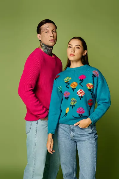 A stylish man and woman confidently show off their bright sweaters in a vibrant display. — Stock Photo