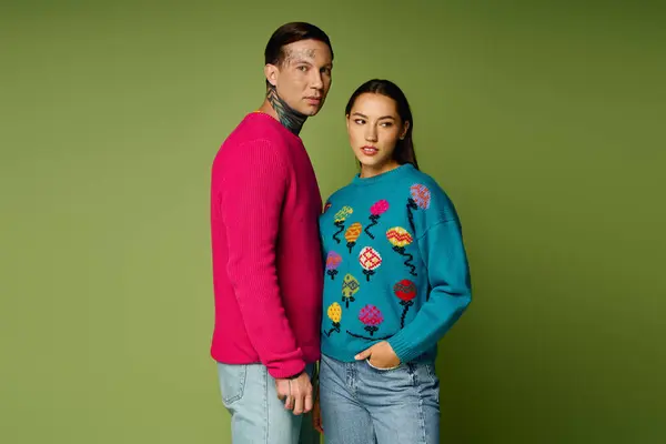 A young couple showcases colorful sweaters, creating a striking visual against the green backdrop. — Stock Photo
