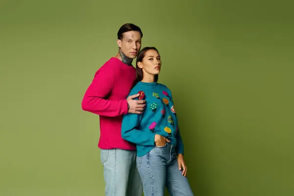 A young couple stands closely, showcasing vibrant fashion choices in a creative setting. — Stock Photo