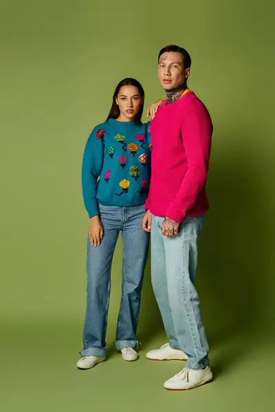 Un jeune duo élégant met en valeur leur mode unique avec des pulls audacieux et des jeans décontractés. — Photo de stock
