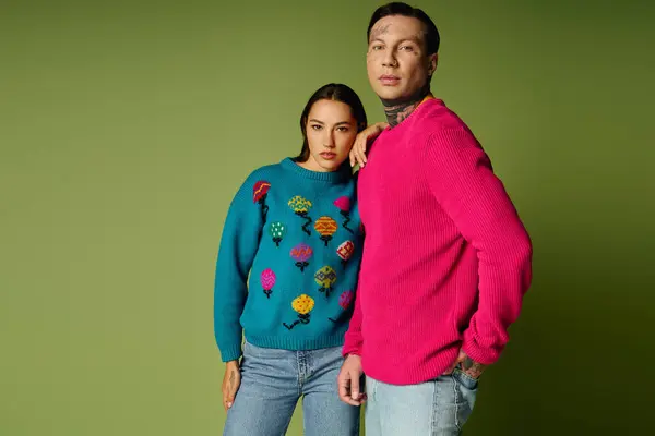 Two fashionable individuals pose confidently in bright sweaters against a striking backdrop. — Stock Photo
