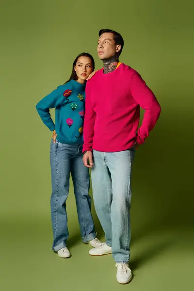 A stylish young couple showcases their outfits with playful expressions in bright colors. — Stock Photo
