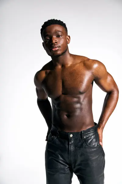 In a studio setting, a young handsome African American man showcases his toned physique while standing confidently. His striking presence captures attention with a sense of empowerment. — Stock Photo