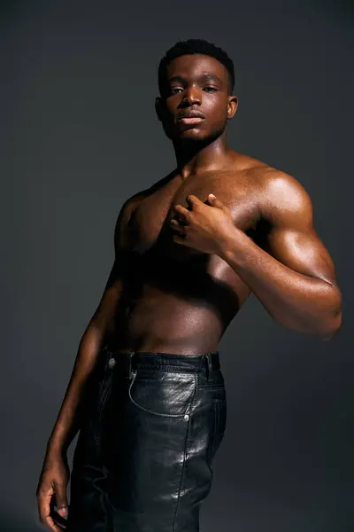 A young handsome African American man poses topless, showcasing his well defined physique in a captivating black and white studio. His strong stance reflects confidence and charisma. — Stock Photo