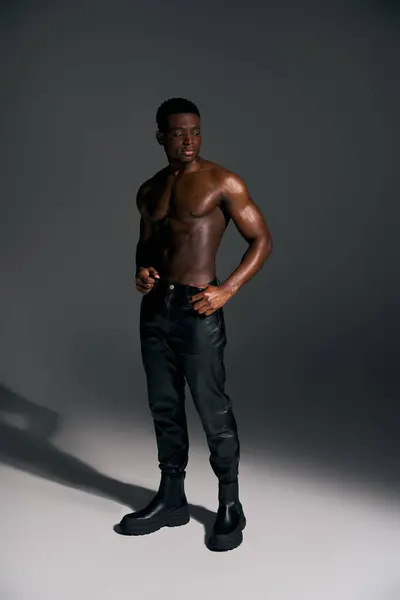 Um jovem afro-americano posa confiantemente com uma postura poderosa, mostrando seu corpo tonificado e um moderno senso de estilo. — Fotografia de Stock