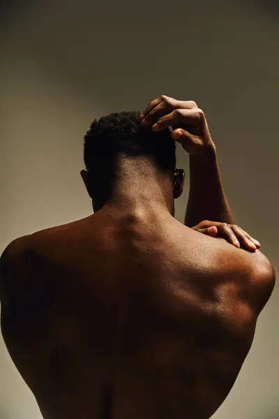 A young, handsome African American man poses confidently without a shirt, showcasing his toned physique. The soft lighting accentuates his features and creates a warm atmosphere. — Stock Photo