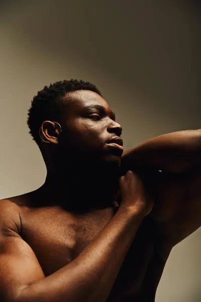A young, handsome African American man confidently poses topless, showcasing his strength and elegance. The soft lighting enhances his features while creating an intimate atmosphere. — Stock Photo