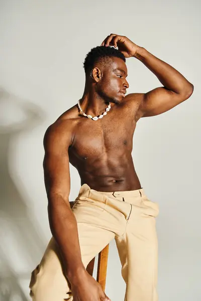 A young, handsome African American man poses confidently topless with a relaxed demeanor. He exhibits a strong physique and wears a stylish necklace, embodying contemporary fashion. — Stock Photo