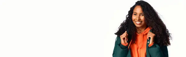 Charming woman with curly hair brightens the space while wearing a trendy outfit and smiling. — Stock Photo