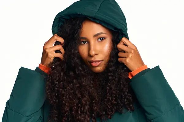 Striking a pose, a woman with curly hair wears a cozy green coat while showcasing her style. — Stock Photo