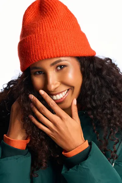 Donna gioiosa con i capelli ricci indossa un cappello arancione e sorride calorosamente, irradiando felicità e stile — Foto stock