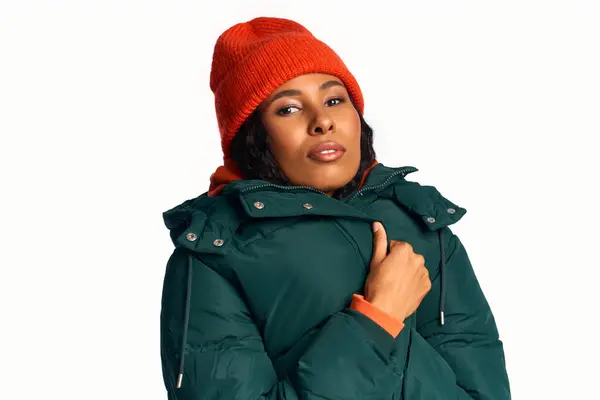 Une femme élégante modélise avec confiance un manteau d'hiver vert et un bonnet vibrant pour la saison. — Photo de stock