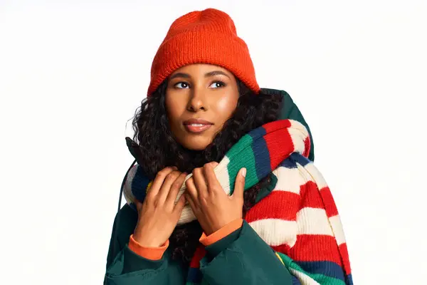 A lovely woman with curly hair showcases her style in vibrant winter clothing and hat. — Stock Photo