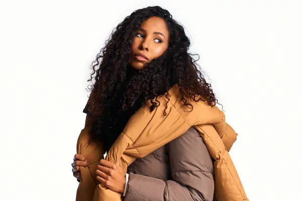 A stunning woman with elegant curls poses gracefully in stylish outerwear, radiating confidence. — Stock Photo