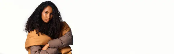 Curly haired woman models chic layers, exuding confidence in a warm, inviting atmosphere. — Stock Photo