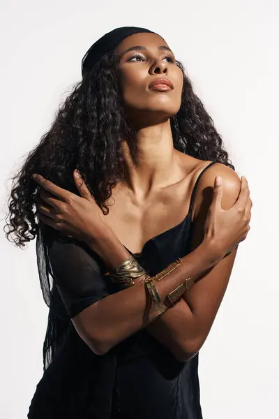 A captivating woman poses elegantly, arms wrapped around herself. — Stock Photo