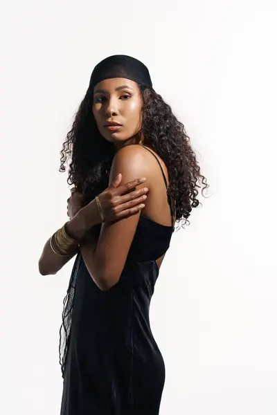 A graceful woman in a sleek black outfit poses with a poised expression and flowing curls. — Stock Photo