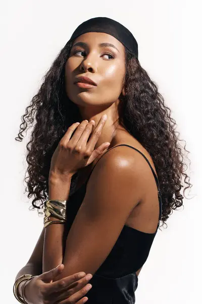 A poised woman with curly hair and jewelry exudes elegance in a creative portrait. — Stock Photo
