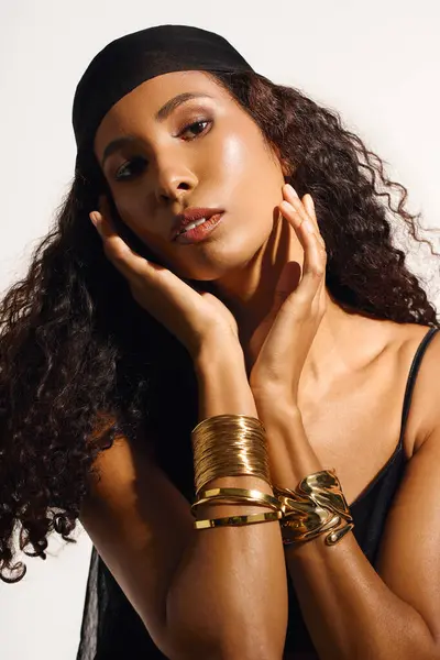 Elegant woman poses gracefully, featuring subtle expression and striking gold jewelry. — Stock Photo