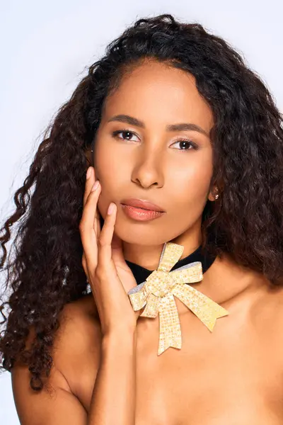 A striking woman poses gracefully, highlighting her radiant features and stylish bow accessory. — Stock Photo