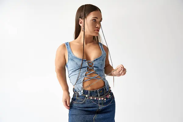 Jeune femme avec achondroplasie porte des vêtements en denim tendance dans un studio lumineux, célébrant la diversité. — Photo de stock