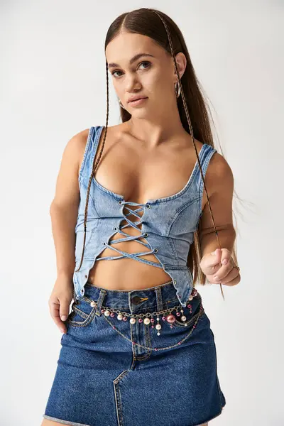 A confident young woman showcases her trendy denim outfit in a stylish studio setting. — Stock Photo