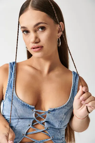 Una joven de baja estatura posa con confianza en el traje de mezclilla de moda, celebrando la diversidad. - foto de stock