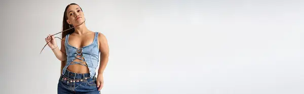 Confident young woman showcases her unique style with fashionable denim in a chic studio setting. — Stock Photo