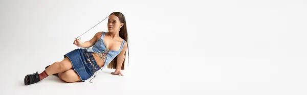A young woman in denim attire poses creatively in a stylish studio environment. — Stock Photo