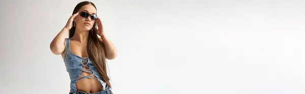 A young woman with short stature confidently models stylish denim clothes in a studio. — Stock Photo
