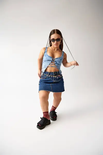 Jeune femme confiante avec des modèles de stature courte tenue denim à la mode tout en posant de manière créative. — Photo de stock
