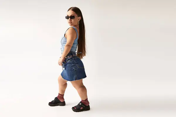 A young woman with achondroplasia showcases unique denim fashion, highlighting diversity and style. — Stock Photo