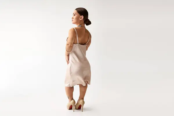 A young woman in an elegant dress poses gracefully in a studio, embodying diversity and style. — Stock Photo