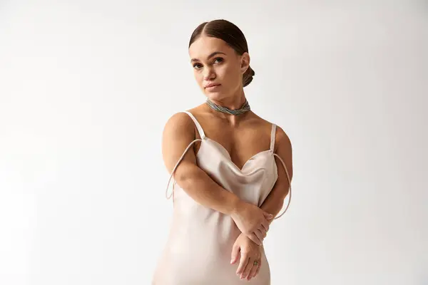 Young woman, embracing diversity, poses gracefully in a beautiful dress against a simple backdrop. — Stock Photo
