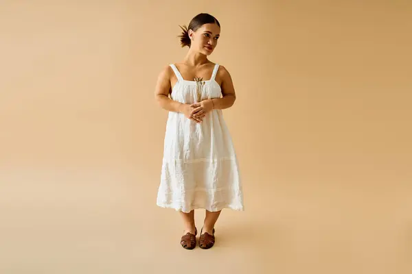 A young woman with short stature models an elegant white dress in a studio setting. — Stock Photo
