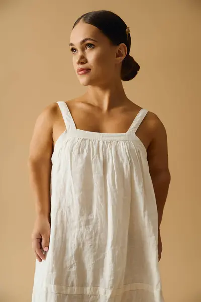 A stylish young woman with short stature poses gracefully in a chic dress in a studio. — Stock Photo