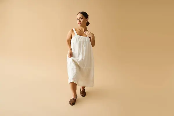 A young woman with short stature gracefully models a beautiful dress in a studio setting. — Stock Photo
