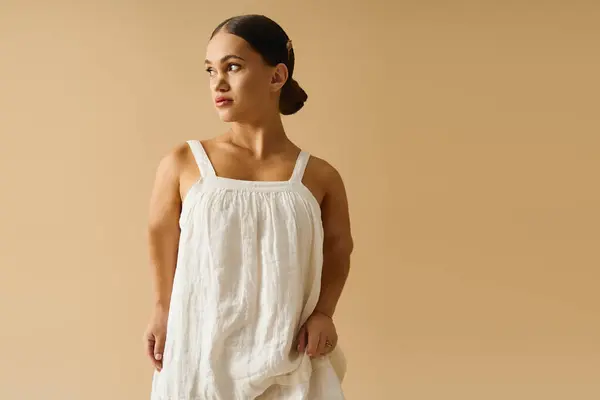 A young woman with short stature poses gracefully in a stylish dress against a soft backdrop. — Stock Photo