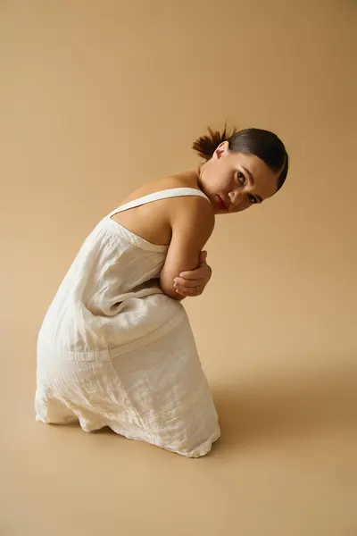 Une jeune femme dans une belle robe pose gracieusement dans un studio, soulignant la diversité. — Photo de stock