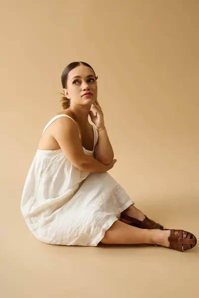 Abraçando sua individualidade, uma jovem se senta graciosamente em um estúdio, irradiando elegância. — Fotografia de Stock